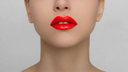 The macro photo of the closed female mouth. Chubby lips with red lipstick show a fashionable...