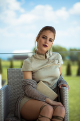 A film portrait of young beautiful woman with dress sitting on the balcony.