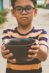 Homeless. Unhappy homeless boy ceramic bowl standing on street to asking help for food donation from the people with hungry and sad.