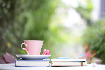 Pastel pink cup with flower and books at outdoor 