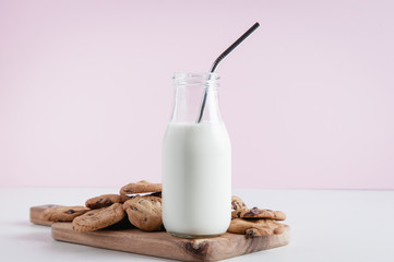 cookies and a bottle of milk with metal straw on a pink background