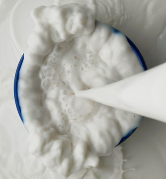 Milk being poured to overflow into bowl