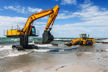 excavator and bulldozer on the beach, building groynes