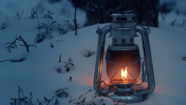 Oil lamp old lantern on snow in forest in winter