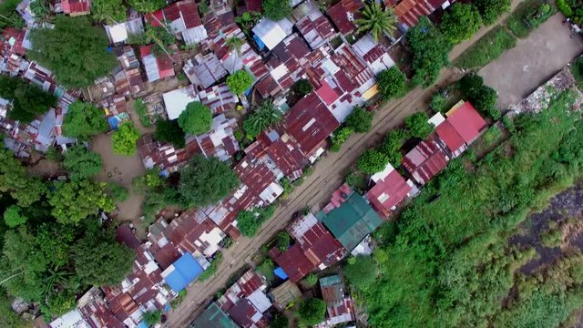San Pablo City, Laguna, Philippines - January 26, 2018: Roofs of slum and squatter houses built along railway road in a messy, ill planned city housing community. drone aerial