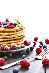 Pancakes with honey and berries on white background