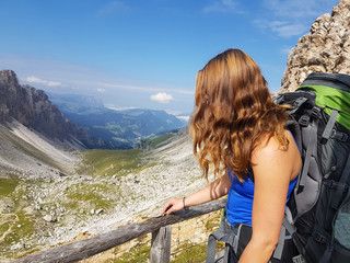 Fototapeta na wymiar Hiker with backpack relaxing on top of a mountain and enjoying valley view during trip in the alps