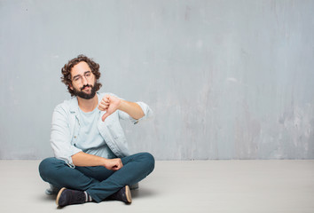 young cool bearded man sitting on the floor. grunge wall background