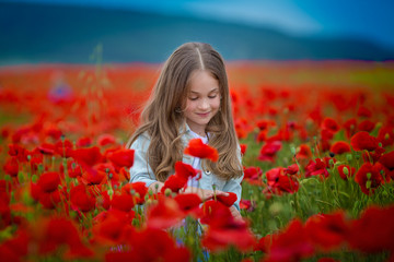 Beauty blue eyes teen enjoy summer days .Cute fancy dressed girl in poppy field. Field of blooming poppies.