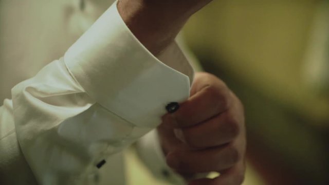 Grooms morning preparation, handsome groom getting dressed and preparing for the wedding, close-up,wearing cufflinks