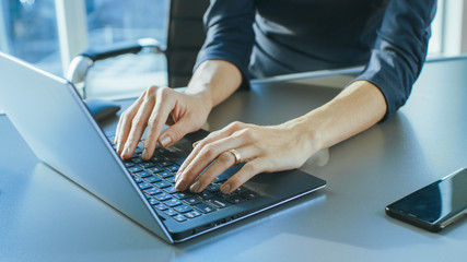 Naklejka na ściany i meble Close-up On the Hands of a Businesswoman Typing on a Laptop Keyboard. Female Using Laptop in the Office.
