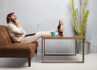 young bearded man sitting on a leather sofa in a vintage living room