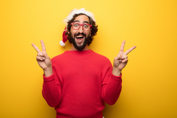 young crazy bearded man wearing red glasses and santa claus hat