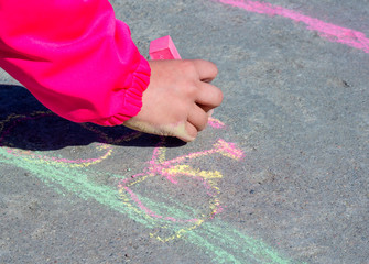 Children's hand draws with chalk on asphalt