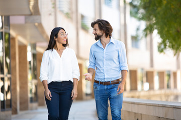 Confident multiethnic friends talking at walking at office building. Professional multicultural...