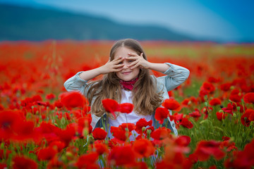 Beauty blue eyes teen enjoy summer days .Cute fancy dressed girl in poppy field. Field of blooming poppies.