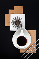 White cup of coffee on a black background in a graphic layout with lines from paper notepad with copy space flat lay top view art trend style