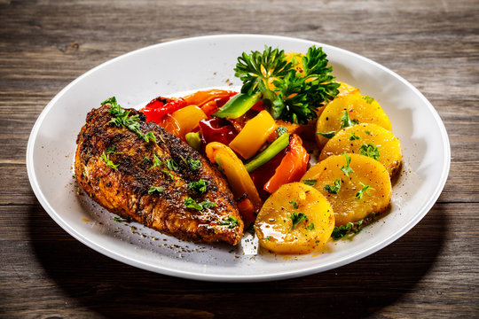 Grilled chicken fillet and vegetables on woowde table