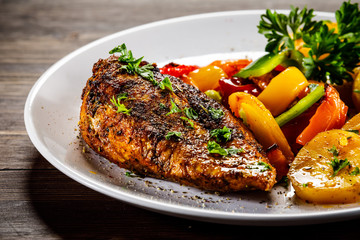 Grilled chicken fillet and vegetables on woowde table