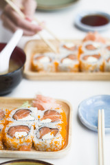 Traditional japanese salmon roll set on wooden plate in restaurant. Hand with chopsticks in background. POV. Lunch, Dinner concept. Text space