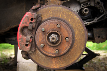 Fototapeta na wymiar rusty brake disc and pad on a broken car in the yard