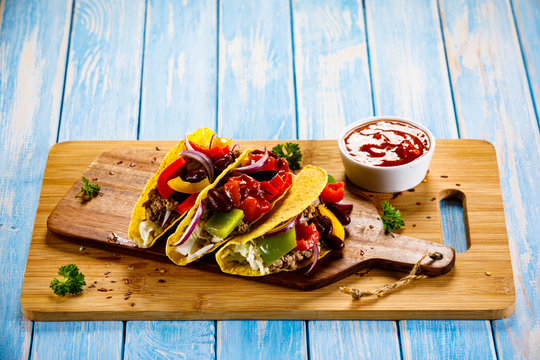 Tacos on cutting board on wooden table
