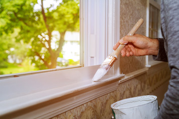 Man painting window trim at home, close-up