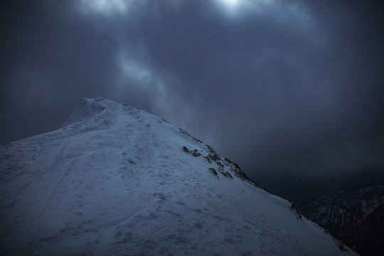 View of snowcapped mountain peak against stormy clouds