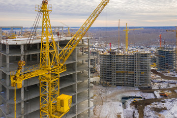Construction crane next to the house under construction from a height, aerial view
