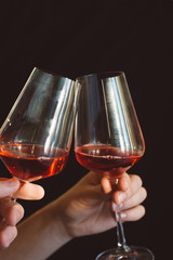 hand holds a glass of fresh red wine on a dark background