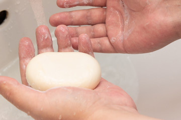 A man washes his hands with soap in the sink.