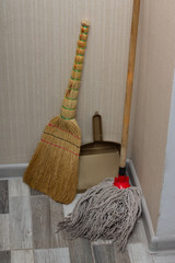 Mop, broom and dustpan in the corner. Hygiene and home cleaning.