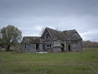 Obraz premium Dreary Abandoned Dilapidated Farm House with cloud skies in northern Minnesota