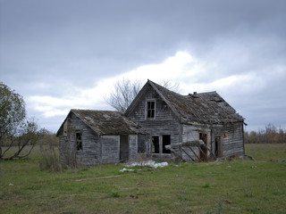 Fototapeta na wymiar Dreary Abandoned Dilapidated Farm House with cloud skies in northern Minnesota