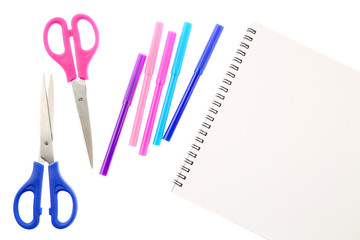 Two scissors, five felt tip pens in pink, blue and purple colors and blank sketchbook, isolated on white background. Space for text on the pad sheet. Art and creativity concept