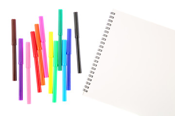 Set of twelve felt tip markers in different colors and a blank sketchbook with a space for text. Isolated on white background. Art and creativity concept