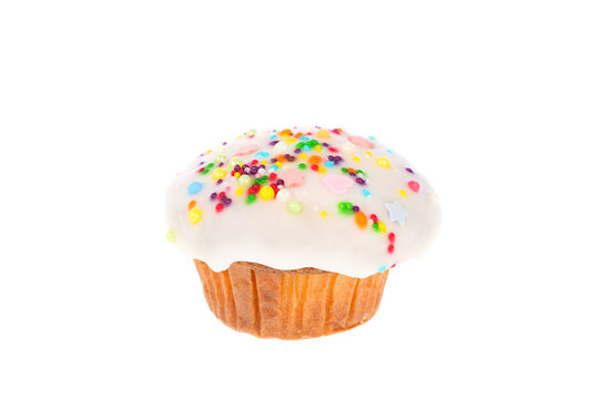 Delicious homemade muffin with white fondant and colorful sugar sprinkles icing isolated on a white background.