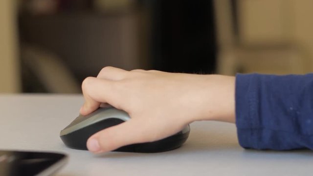 Children's hand clicks on a computer mouse.