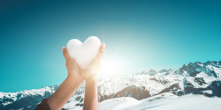 Woman holding up a heart in snowy mountains