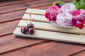 Pink homemade zephyr or marshmallow with cherry berry and flowers on light wooden background. Marshmallow, Meringue, Zephyr. Sweet morning. tasty dessert.Copy space