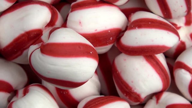 Round red and white peppermint soft candies spinning video close up