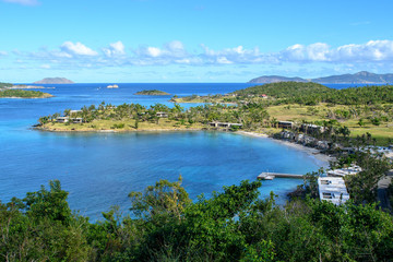 View of the blue lagoon of a tropical island. Green trees, blue sea and blue sky with clouds