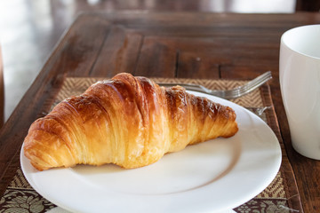 French Croissant on plate for breakfast closeup on wooden table