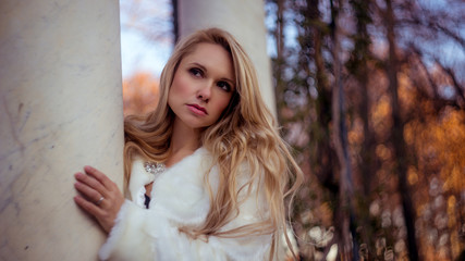 melancholy falling, scene of autumn and winter, beautiful blond woman with gestures of melancholy dressed in grey coat