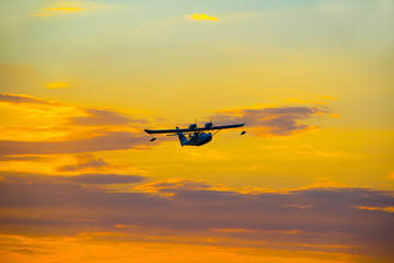 Naklejka na ściany i meble Seaplane with two propellers on the wings against the sky at sunset.