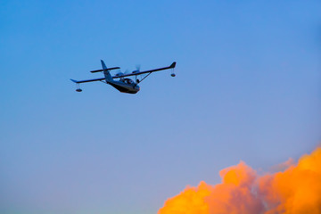Seaplane with two propellers on the wings against the sky at sunset.