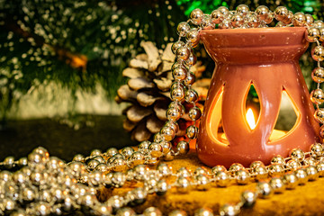 Festive Christmas composition with wax candles, gift boxes and silver beads. Decorations for new year's eve. On a dark background in warm light decorations, cones, stand and lights among the green pin