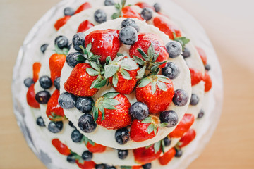 white wedding cake decorated with cherries, strawberries and blueberries