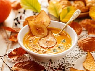 Pumpkin soup with the addition of pear chips in a white ceramic bowl. Delicious and healthy...