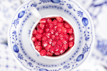 Cup with pomegranate seeds. White and blue dishes. Top view